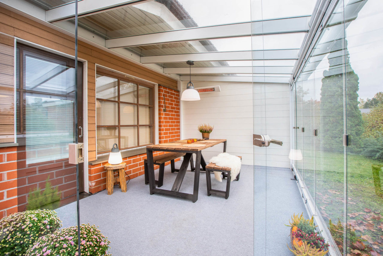 A glass patio enclosure next to a living room and kitchen by Lumon Canada Inc.