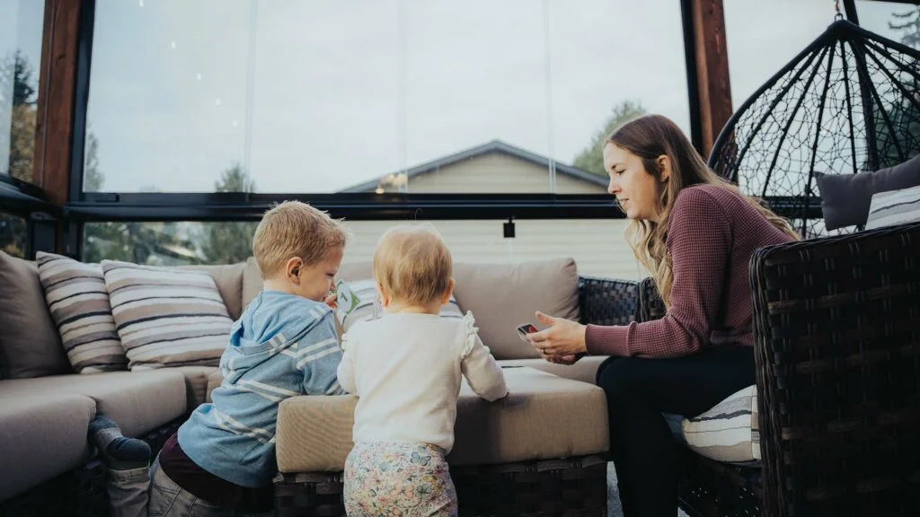 A mother with kids sitting in the sunroom of their home in Greater Vancouver