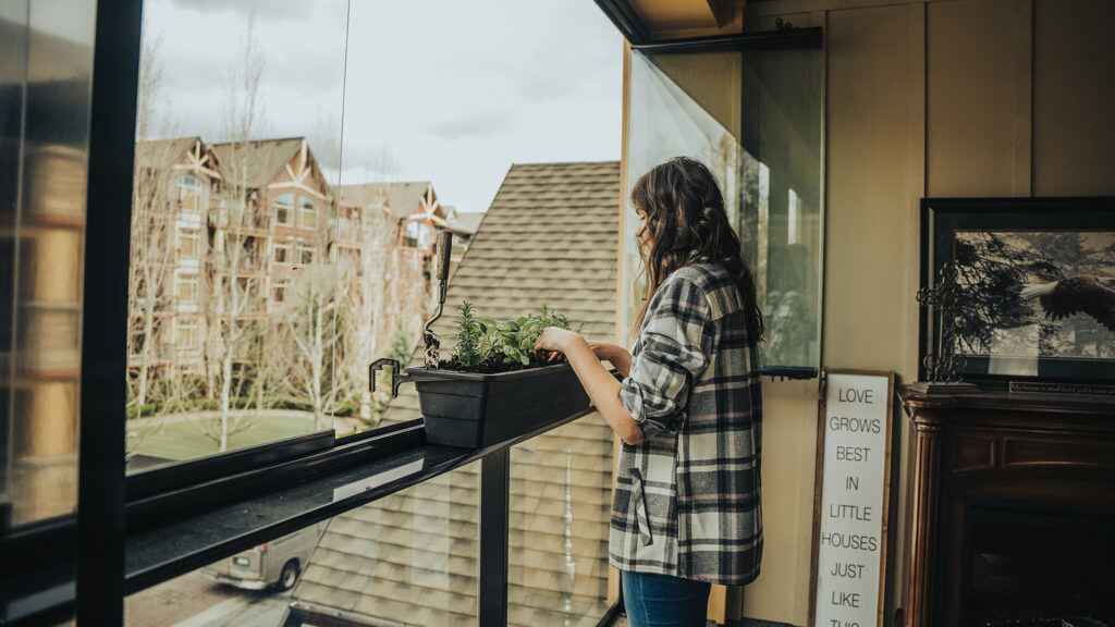 A woman setting up plant at her glazing balcony of her house in Greater Vancouver