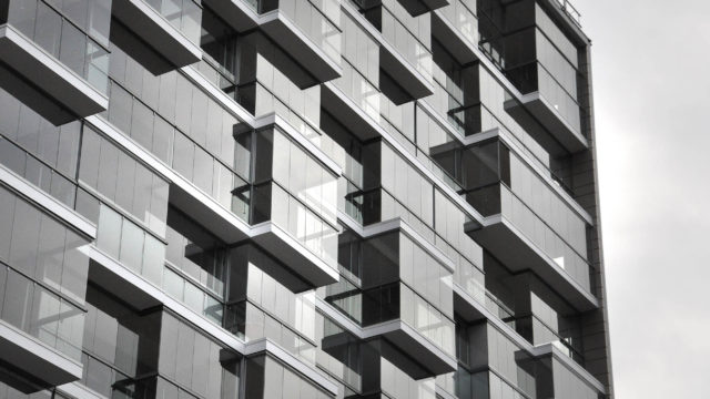 Schwarz-weiß-Bild einer Balkonfassade mit Dreh-/Schiebeverglasung und Glasgeländer in Kombination