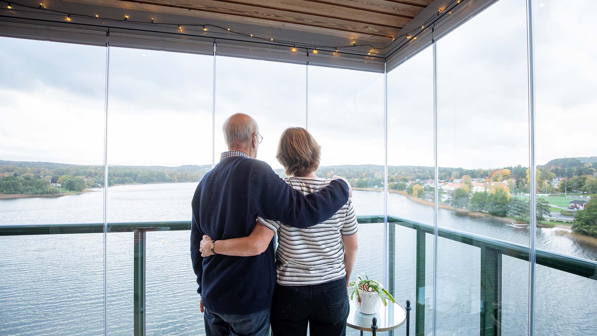 Paar blickt durch Balkonverglasung auf See