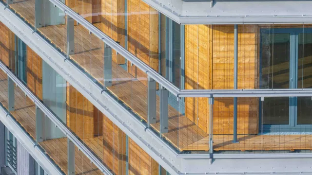 Detailaufnahme eines Balkons des Holzhochhauses roots mit geschlossenen Balkonverglasungen