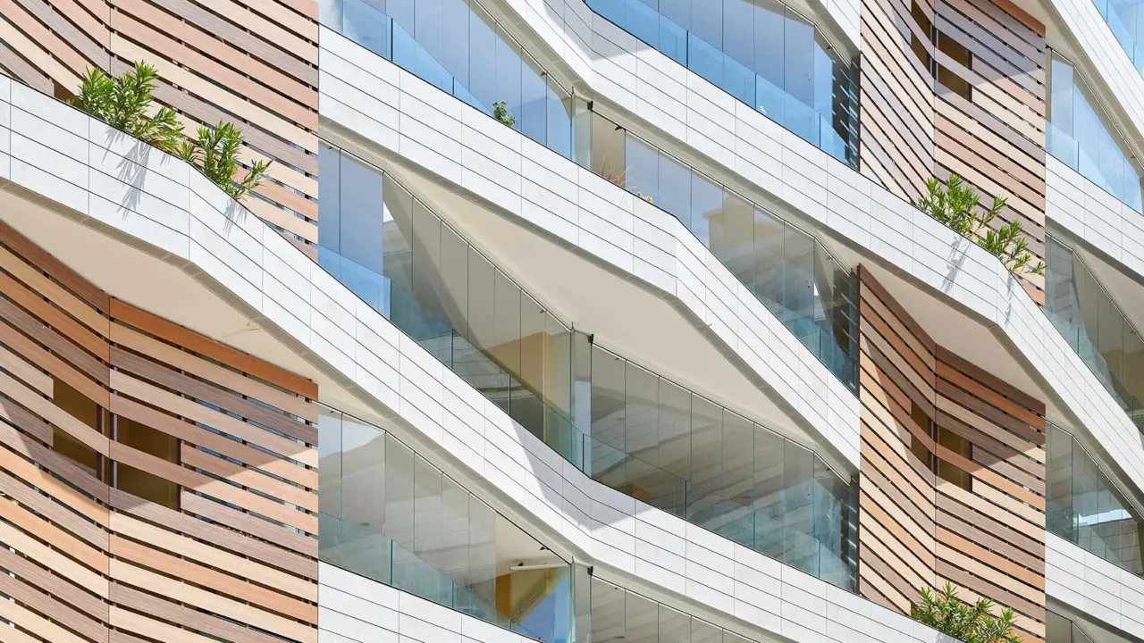 Blick von unten auf eine Fassade mit Holzverkleidung und verglasten Balkonen.
