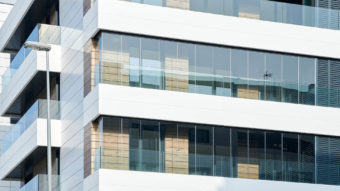 Blick auf drei Etagen eines Mehrfamilienhauses mit einer Balkonfassage aus Glas
