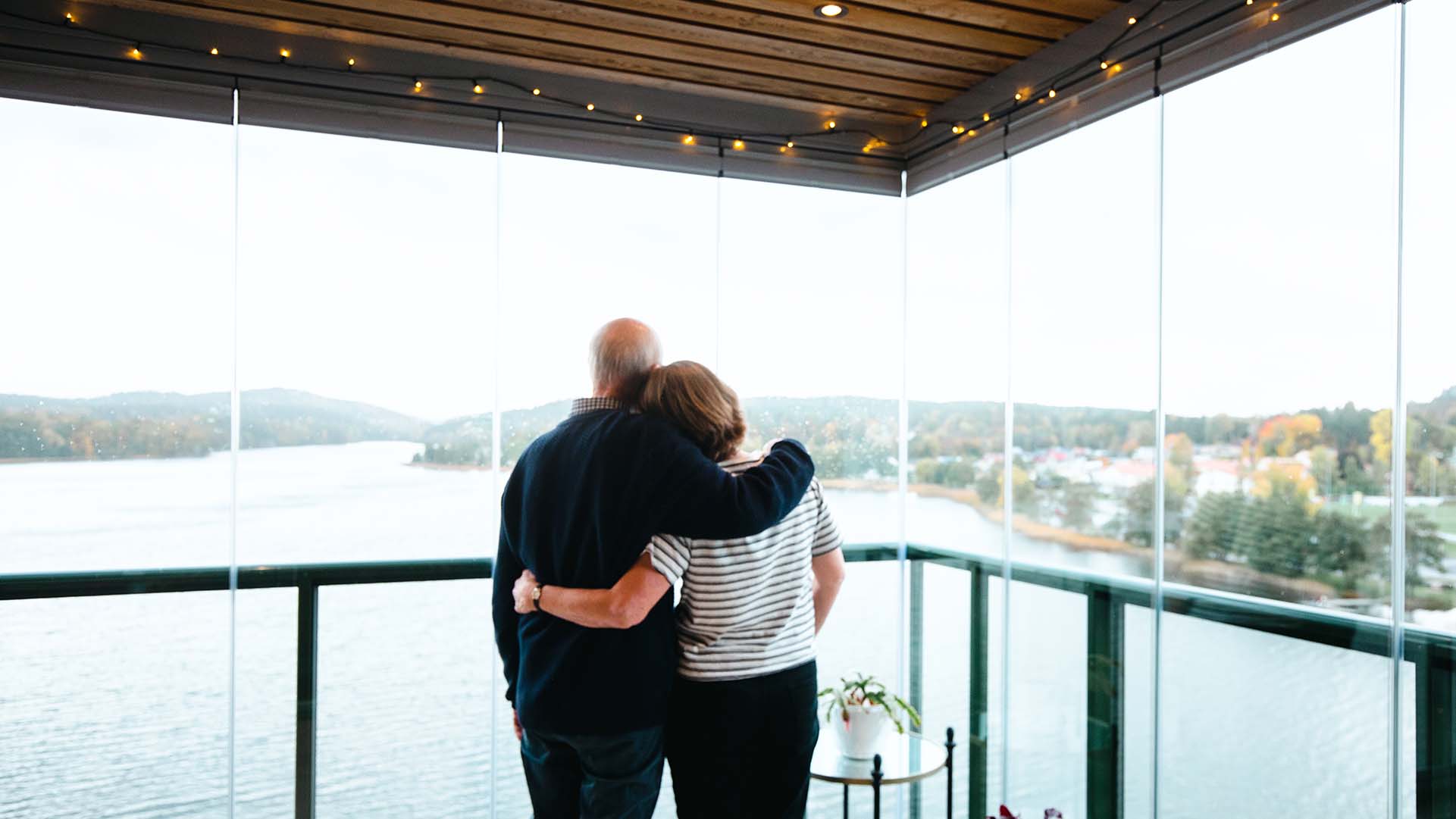 Paar blickt durch Balkonverglasung auf See