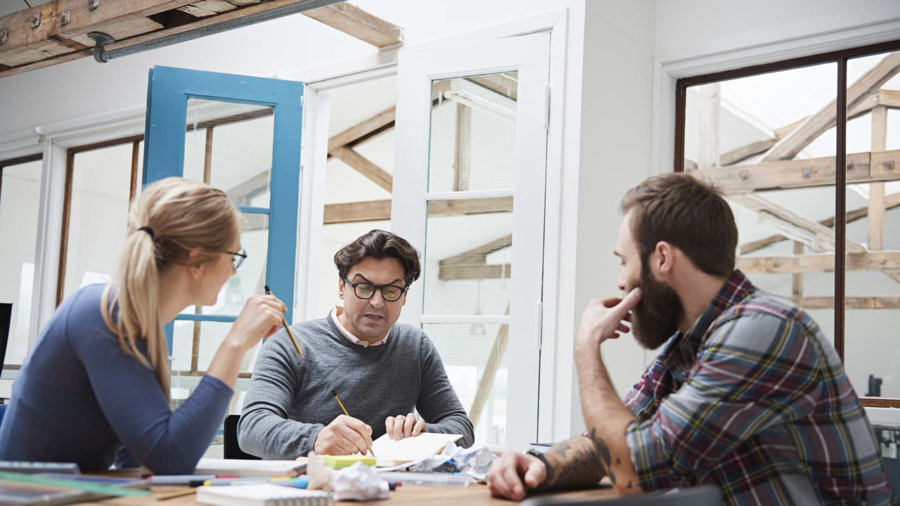 Drei Architekten beim Brainstorming sitzend an einem Arbeitsplatz
