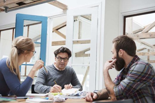 Drei Architekten beim Brainstorming sitzend an einem Arbeitsplatz