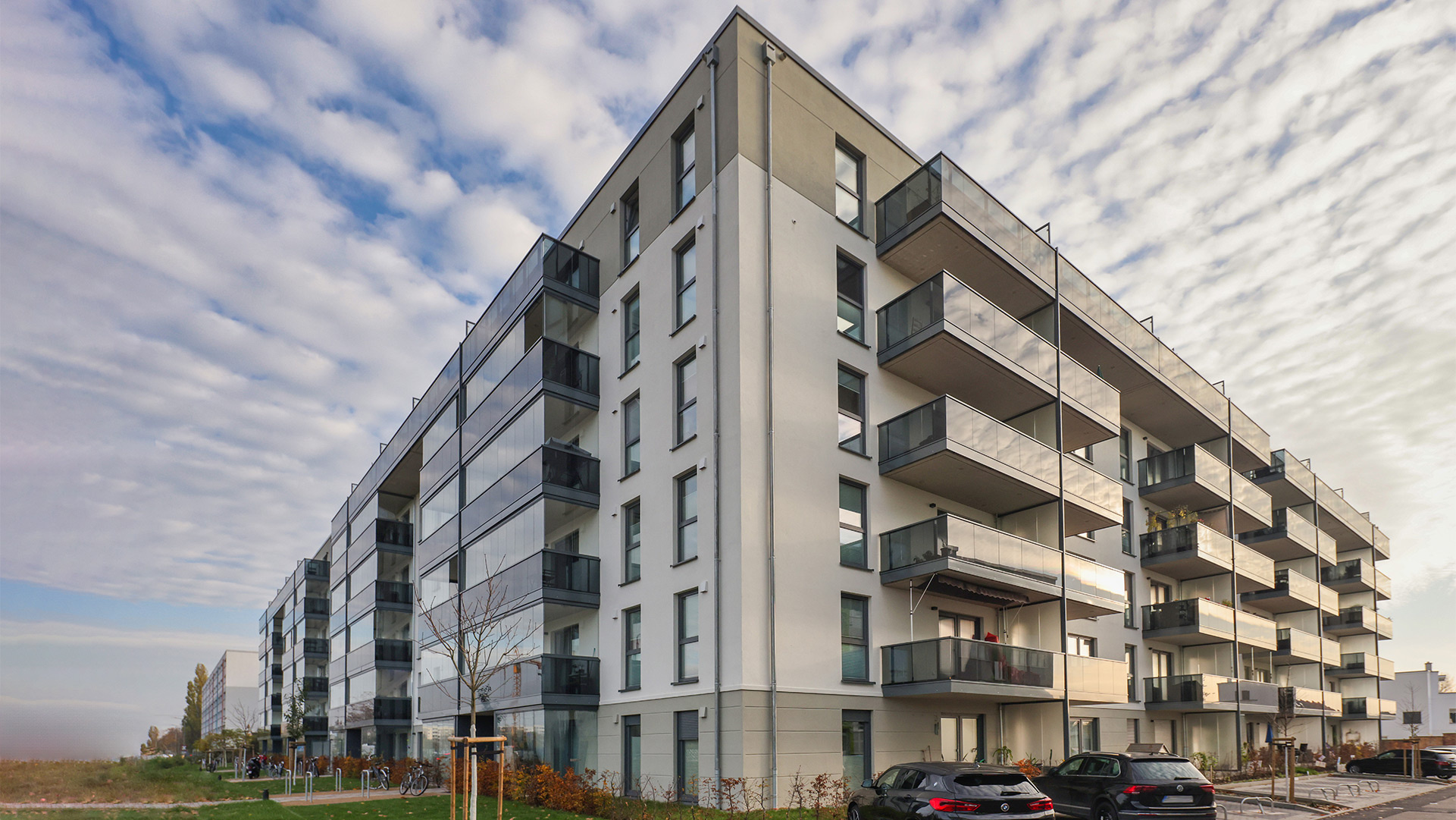 Mehrfamilenhaus mit Balkonverglasungen, die auf Ganzglasgeländer aufgesetzt sind.