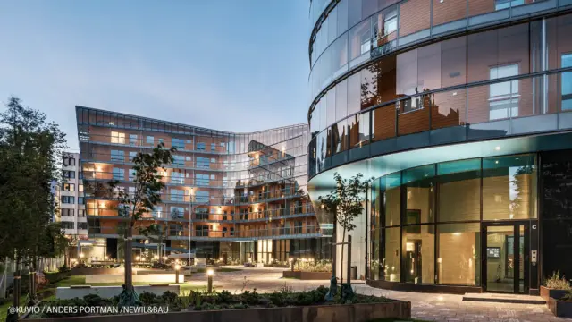 Gebäude mit Balkonfassade bestehend aus Balkonverglasung auf einem Ganzglasgeläner aufgesetzt. Hinter den Verglasungen befinden sich Holzbalkone.