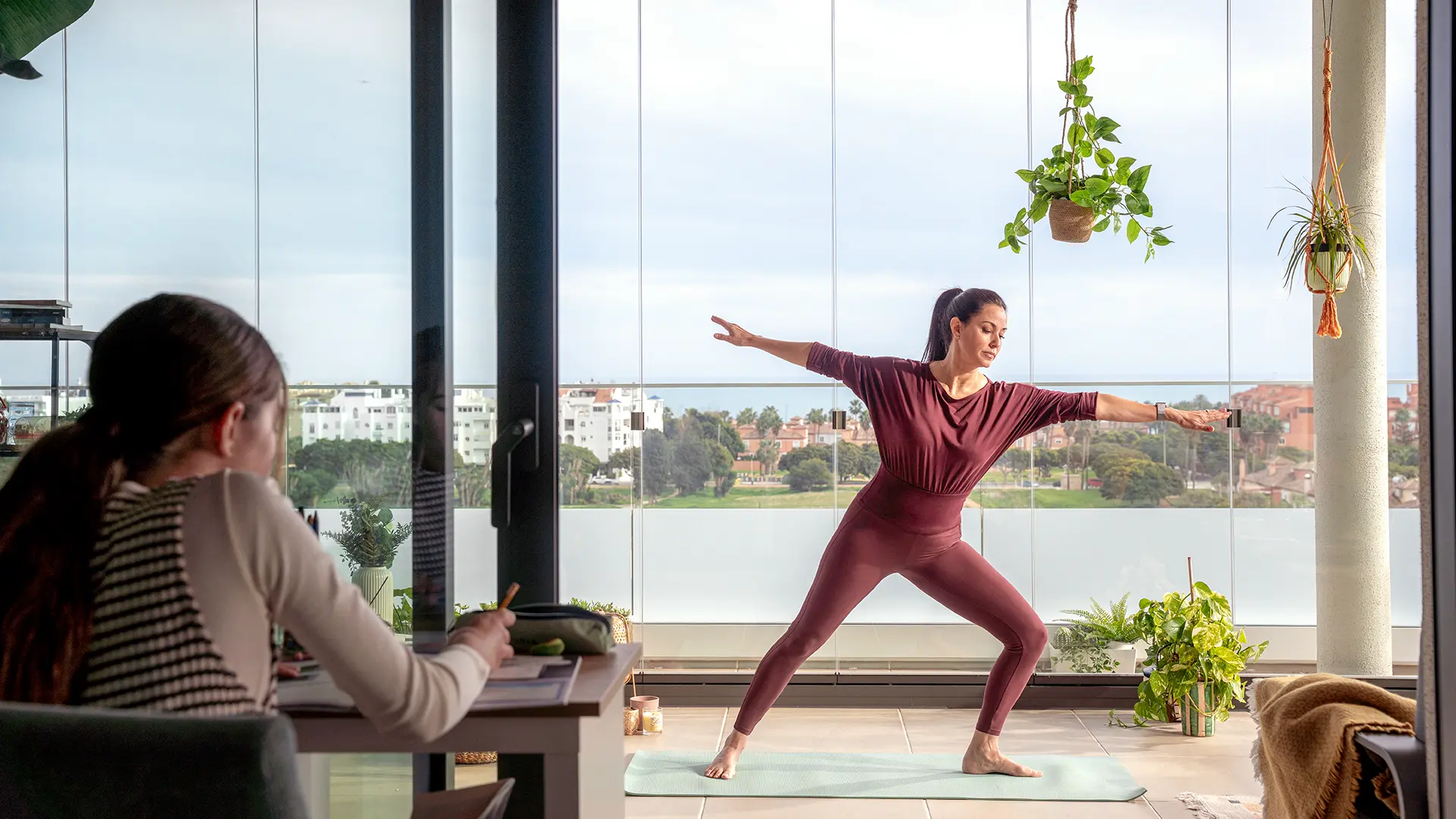 Eine Frau macht Yoga auf ihrem verglasten Balkon