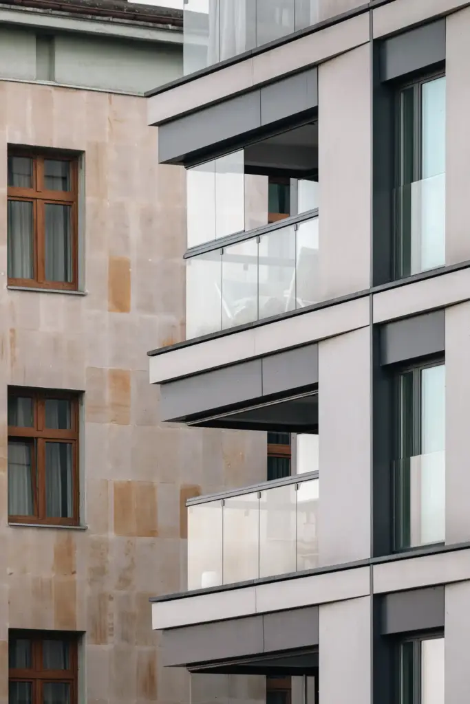Blick auf einen Ausschnitt eines Mehrfamilienhauses. Zu sehen sind zwei Balkone von der Seite mit Balkonverglasungen
