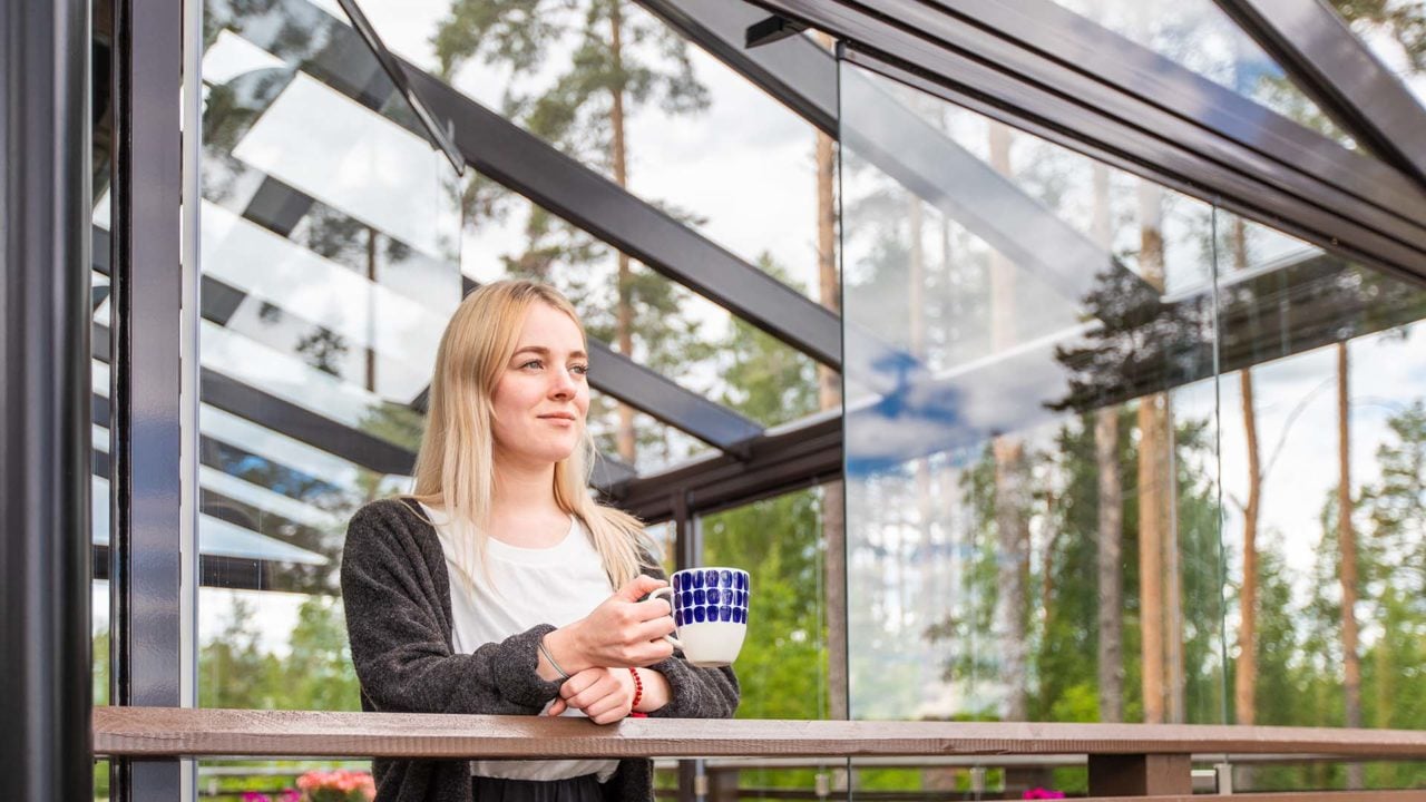 nainen aamukahvilla lasitetulla terassilla, Lumon terassilasitus