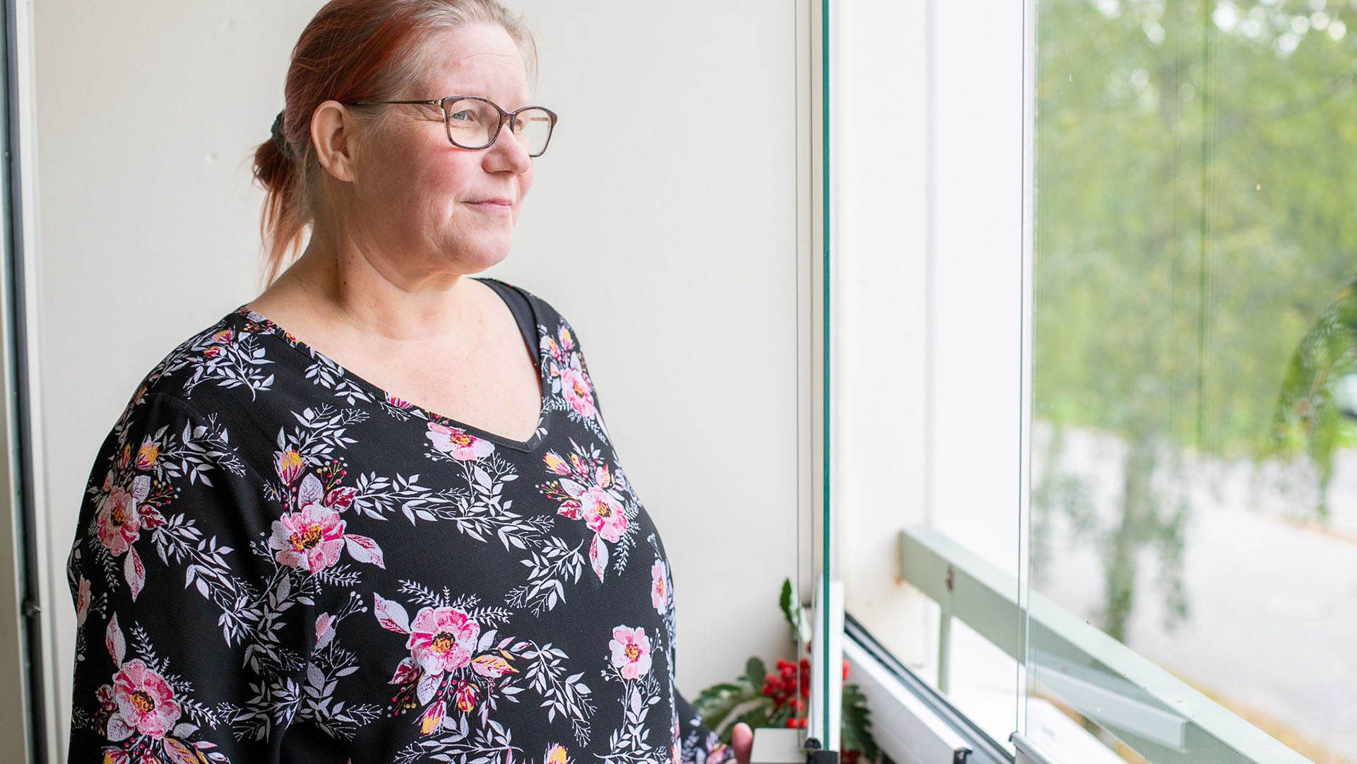 Lumon parvekelasitus, nainen katsoo kaukaisuuteen lasitetulla parvekkeella