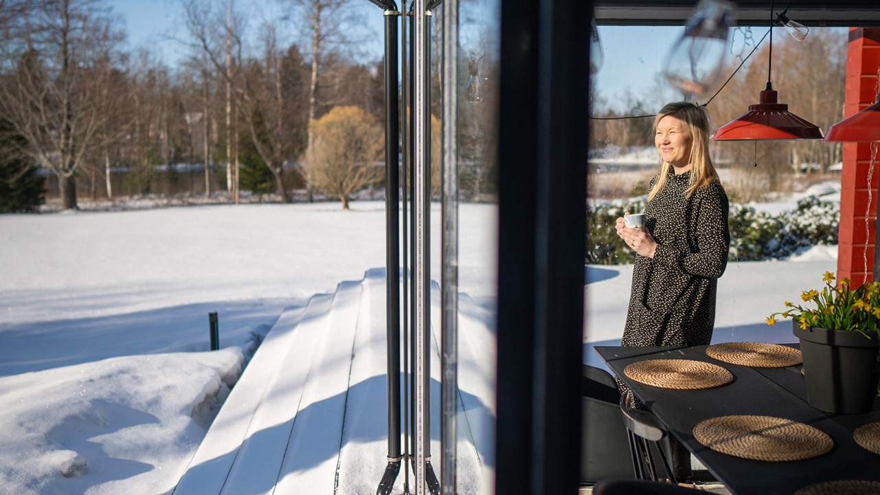 nainen katsoo lasituksesta ulos, nainen lasitetulla terassilla