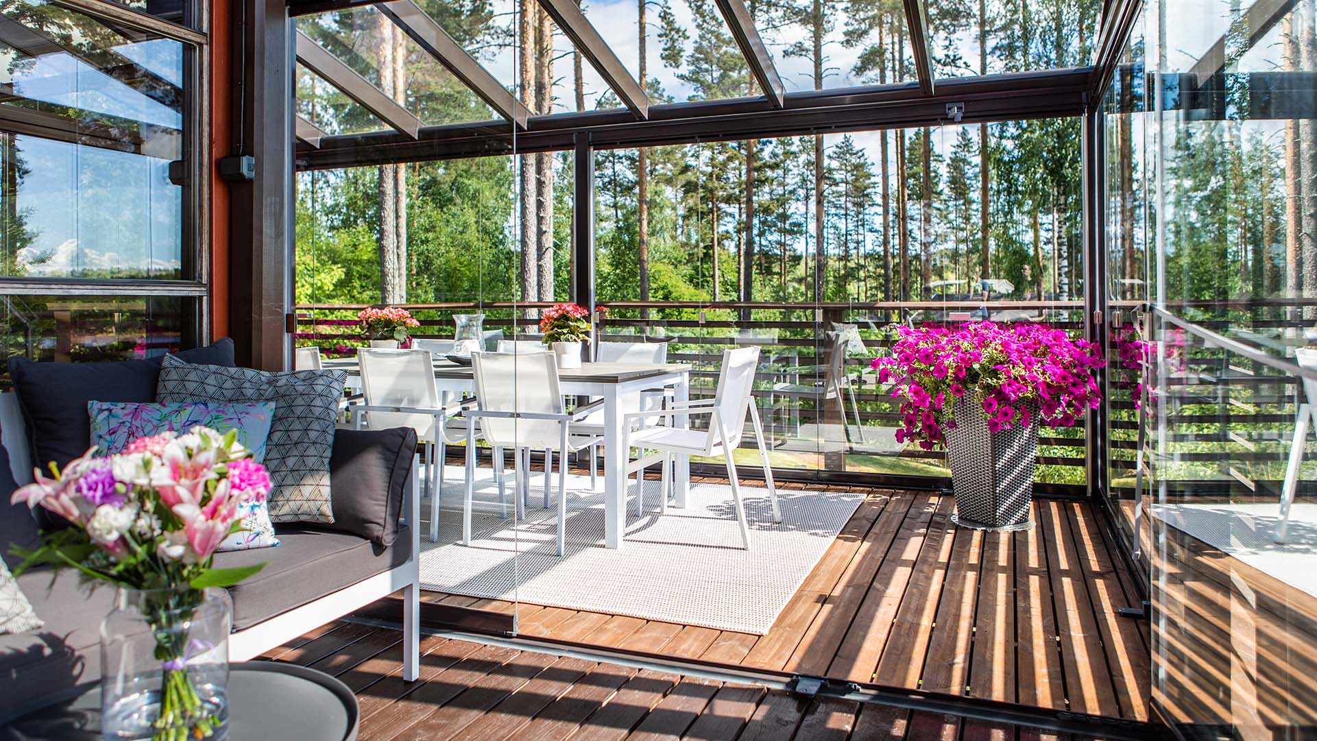 Table de salle à manger et arrangements floraux roses sur une terrasse avec un vitrage de terrasse Lumon