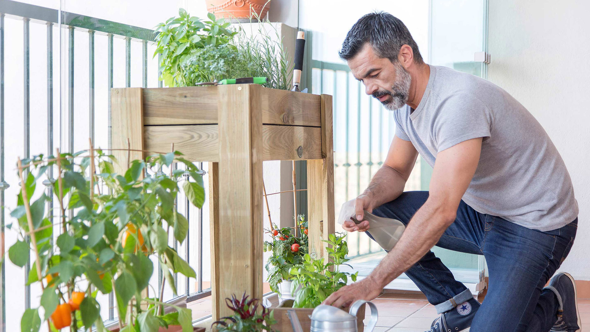 Un homme asperge des plantes sur une loggia vitrée