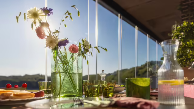 Vase de fleurs et assiette sur une table sur un balcon vitré