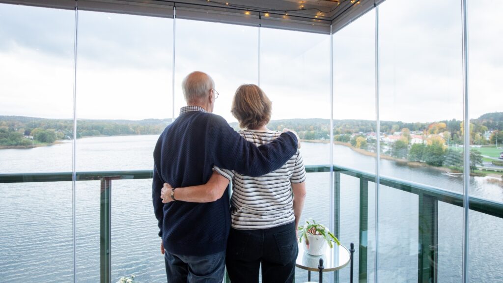 Couple overlooking a lake from a balcony with balcony glazing